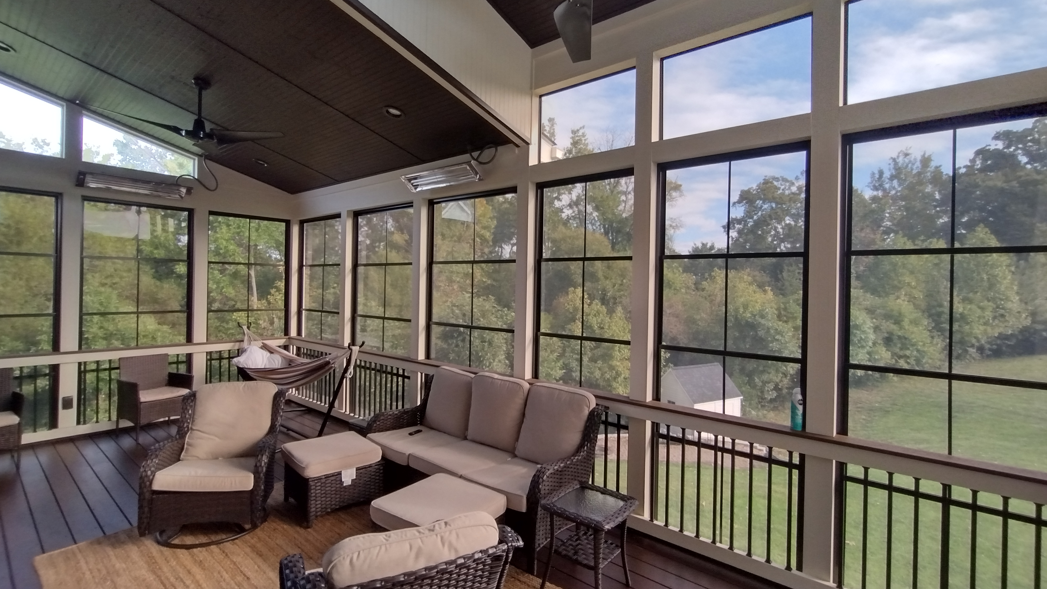 A bright Eze Breeze porch with a sectional sofa and large windows looking out on a green yard